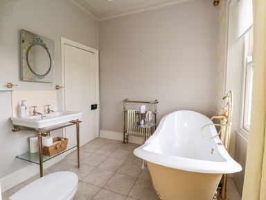 A bathroom with a bathtub a sink with toiletries and a mirror at The Stables and West Wing Bolton Percy near Tadcaster