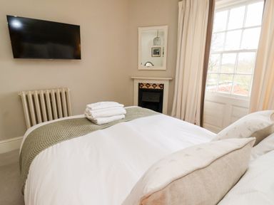 A bedroom with a bed TV radiator mirror and window at The Stables and West Wing Bolton Percy near Tadcaster