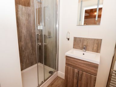 A bathroom with a corner shower enclosure and a sink with wooden cabinet at The Stables and West Wing Bolton Percy near Tadcaster