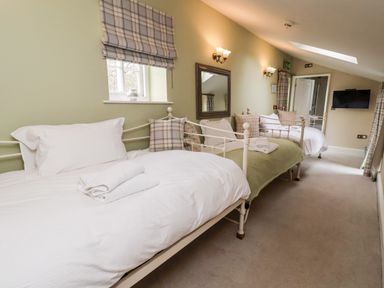 A bedroom with two single beds a wall mirror and a tv at The Stables and West Wing Bolton Percy near Tadcaster