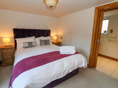 A bedroom with a bed with folded towels bedside tables with lamps and an open door to a bathroom at Servant's Quarters Bolton Percy near Tadcaster
