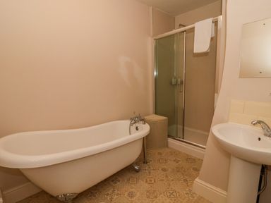 A bathroom with a clawfoot bathtub a shower with a glass door a pedestal sink and a laundry basket at Servant's Quarters in Bolton Percy near Tadcaster