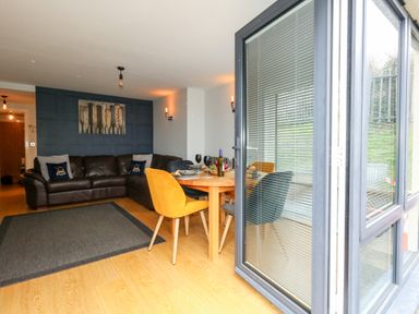 A living room with a brown leather sofa and a dining table with yellow and grey chairs at Pointers View in Weymouth
