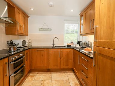 A kitchen with wooden cabinets a stove microwave sink and window at Pointers View in Weymouth
