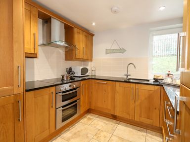A kitchen with wooden cabinets a stove a microwave and a sink at Pointers View in Weymouth