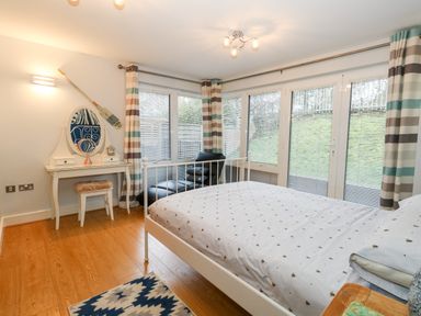 A bedroom with a bed a chaise lounge a dressing table with a mirror and striped curtains at Pointers View in Weymouth
