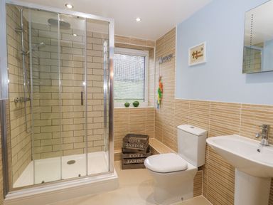 A bathroom with a shower cubicle toilet sink window and decorative crates at Pointers View in Weymouth