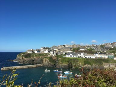 A coastal village with houses on cliffs and boats in the water at Mermaid Cottage in Port Isaac