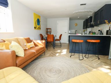 An open plan living room and kitchen with a sofa dining table and kitchen island at Flat 6 Thornlow Heights in Weymouth