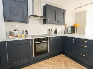 A kitchen with blue cabinets white marble countertops a stove oven toaster kettle and mugs at Flat 6 Thornlow Heights in Weymouth