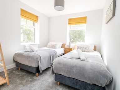 A bedroom with two single beds and yellow window blinds at Flat 6 Thornlow Heights in Weymouth