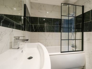 A bathroom with a sink and bathtub with a glass shower screen at Flat 6 Thornlow Heights in Weymouth