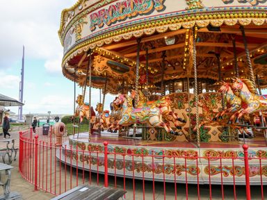A carousel with decorated horses and a red fence around it at an outdoor location