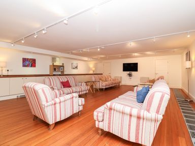 A sitting room with striped sofas wooden floor and a wall-mounted TV at The Old Gymnasium in Southwold