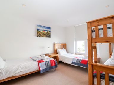 A bedroom with three single beds and a bunk bed with patchwork quilts at The Old Gymnasium Southwold