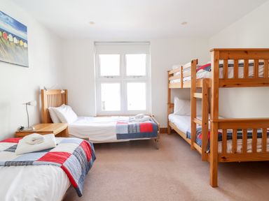 A bedroom with a single bed bunk bed wooden furniture and a window at The Old Gymnasium in Southwold