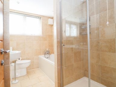 A bathroom with a toilet sink bathtub and a shower enclosure at The Old Gymnasium in Southwold
