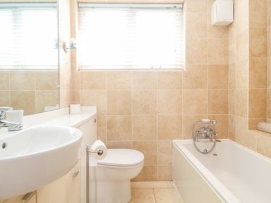 A bathroom with a sink toilet bathtub and window with blinds at The Old Gymnasium in Southwold