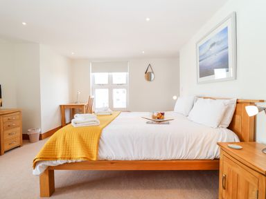 A bedroom with a wooden bed with white bedding and a yellow throw at The Old Gymnasium in Southwold