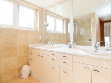 A bathroom with two sinks a large mirror and cabinets below at The Old Gymnasium in Southwold