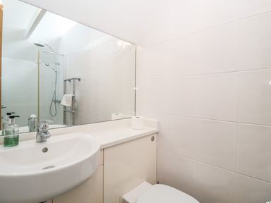 A bathroom with a sink toilet large mirror shower and towel rail at The Old Gymnasium in Southwold