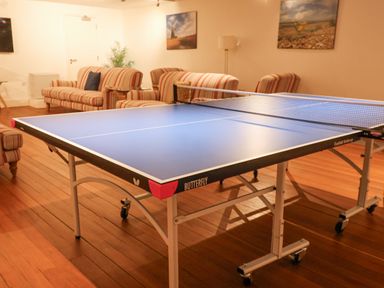 A room with a ping pong table and striped sofas with paintings on the walls at The Old Gymnasium in Southwold