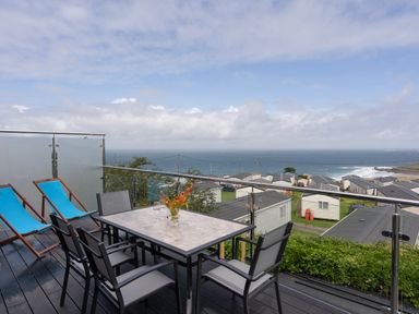 A balcony with a table and chairs overlooking houses and the sea at Treen in St Ives