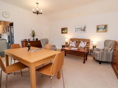 A living room with a wooden dining table and chairs and a seating area with a sofa and armchairs at 6 Granary Court York