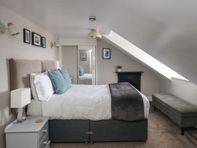 A bedroom with a bed a nightstand a bench a mirrored wardrobe and wall decorations at The Esplanade in Weymouth