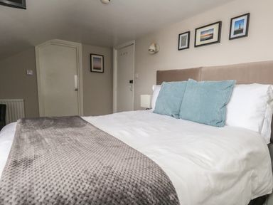 A bedroom with a bed with cushions and a blanket and framed pictures on the wall at The Esplanade in Weymouth