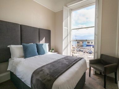 A bedroom with a bed and pillows next to a window with a view at The Esplanade in Weymouth