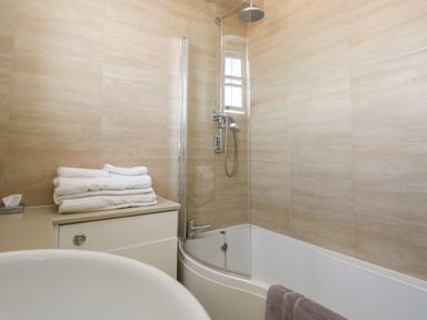 A bathroom with a bathtub shower and towels on a countertop at The Esplanade in Weymouth