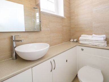 A bathroom with a round basin sink faucet stacked towels and a toilet at The Esplanade in Weymouth