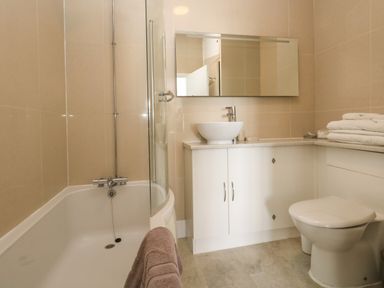 A bathroom with a bathtub towel toilet sink countertop and mirror at The Esplanade in Weymouth