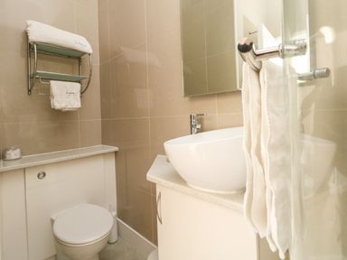 A bathroom with a toilet sink with countertop wall-mounted towel rack and mirror at The Esplanade in Weymouth