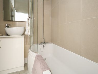 A bathroom with a bathtub a shower a countertop basin and mirror at The Esplanade in Weymouth
