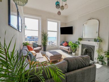A living room with sofas cushions plants and a fireplace with a mirror above at The Esplanade in Weymouth