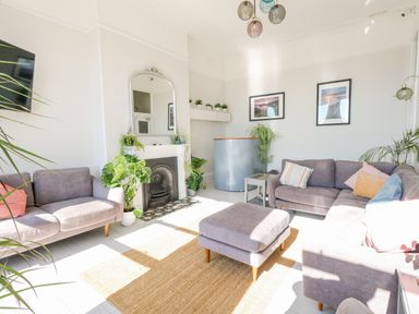A living room with grey sofas a mirror over a fireplace and plants at The Esplanade in Weymouth