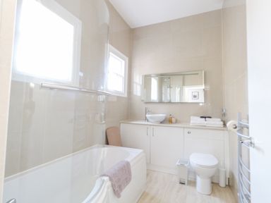 A bathroom with a bathtub shower toilet and sink at The Esplanade in Weymouth