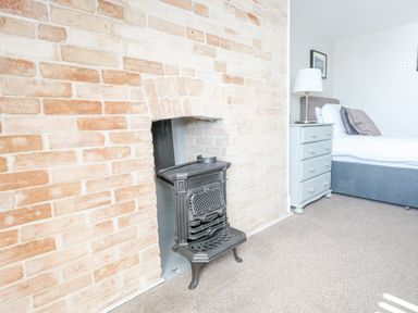 A bedroom with a brick fireplace a grey chest of drawers a white lamp and a bed at The Esplanade in Weymouth