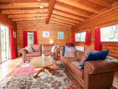 A living room with two brown sofas a wooden coffee table and red curtains at Rocksite in Kirkmichael Perth And Kinross