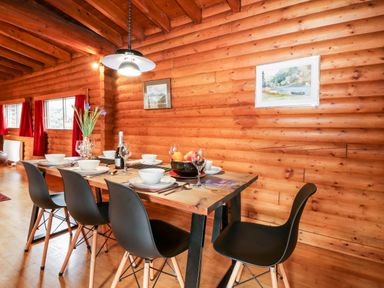 A dining table with black chairs set with bowls glasses and a fruit bowl in a wooden log cabin at Rocksite in Kirkmichael Perth And Kinross