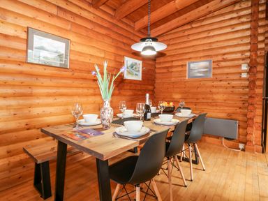 A dining table set with bowls glasses and a vase with flowers in a wooden room at Rocksite in Kirkmichael Perth And Kinross