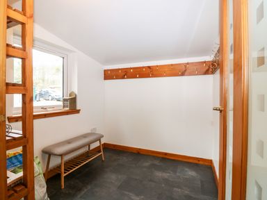 A room with a window bench a wooden coat rack with hooks and a small bench with a shelf below at Rocksite in Kirkmichael Perth And Kinross