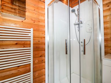 A shower enclosure with glass doors and wooden walls in a bathroom at Rocksite in Kirkmichael Perth And Kinross