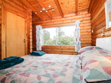 A bedroom with a bed covered with patterned bedding and folded towels on it next to a window with curtains at Rocksite Kirkmichael Perth And Kinross