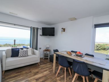 A living room with a sofa and dining table at Sunset Sea View Chalet in Millbrook