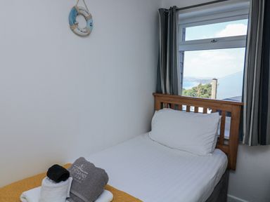 A bedroom with a single bed and towels at Sunset Sea View Chalet in Millbrook