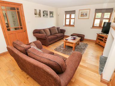 A living room with two brown sofas a wooden coffee table a rug and a television at Ty Melyn in Boncath