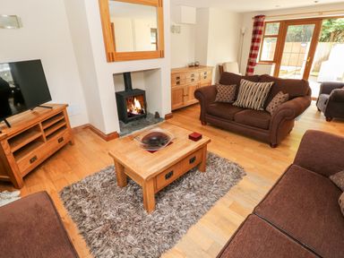 A living room with brown sofas a wooden coffee table and a fireplace at Ty Melyn in Boncath
